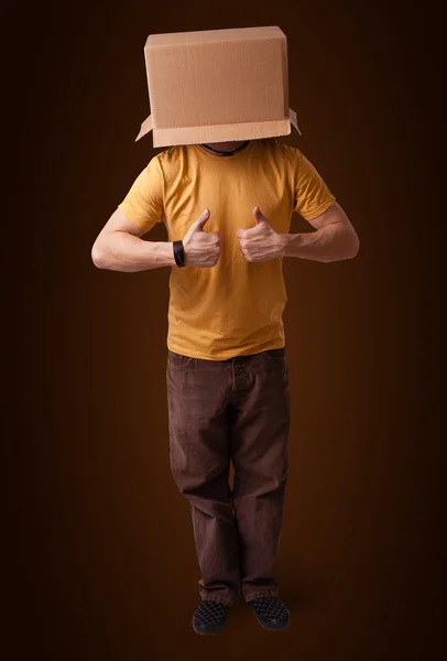 Young man gesturing with a cardboard box on his head — Stock Photo, Image