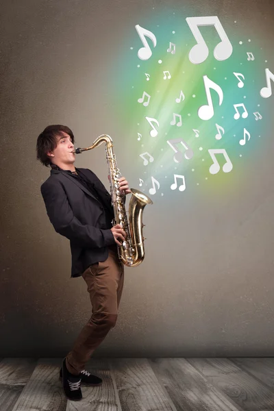 Jeune musicien jouant sur saxophone tandis que les notes de musique explosent — Photo