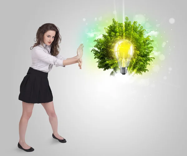 Young girl presenting idea light bulb with green tree — Stock Photo, Image