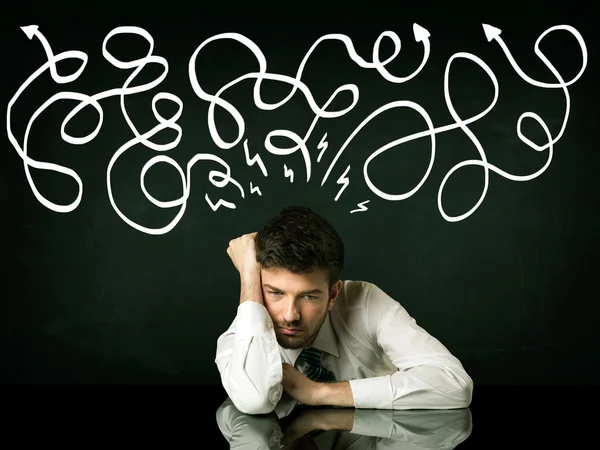 Depresivní podnikatel sedící pod kreslenými směrovými čárami — Stock fotografie