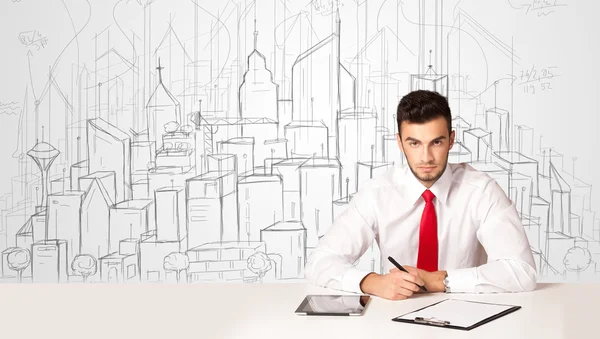 Empresario sentado en la mesa blanca con edificios dibujados a mano —  Fotos de Stock