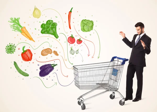 Businessman with shopping cart with vegetables — Stock Photo, Image