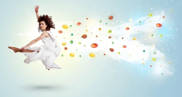 Beautiful woman jumping with colorful gems and crystals on the b