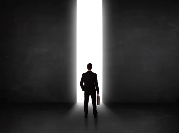 Pessoa de negócios olhando para a parede com abertura do túnel de luz — Fotografia de Stock