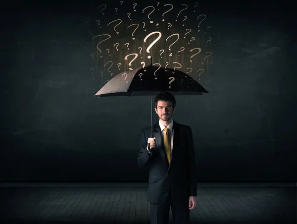 Homme d'affaires avec parapluie et beaucoup de points d'interrogation tirés — Photo