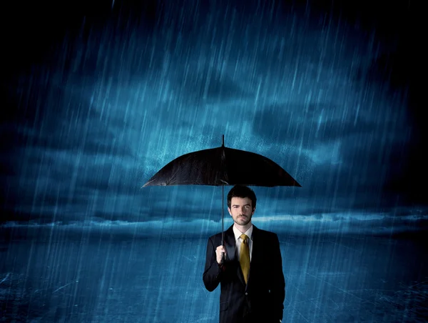 Business man standing in rain with an umbrella — Stock Photo, Image