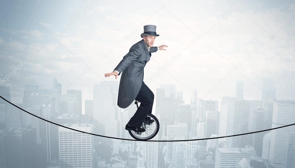 Brave guy riding a monocycle on a rope above cityscape