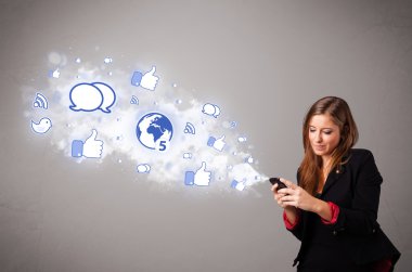 Sosyal medya simgeleriyle telefon tutan güzel bir genç kız.