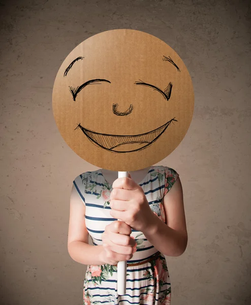 Young woman holding a smiley face board — Stock Photo, Image