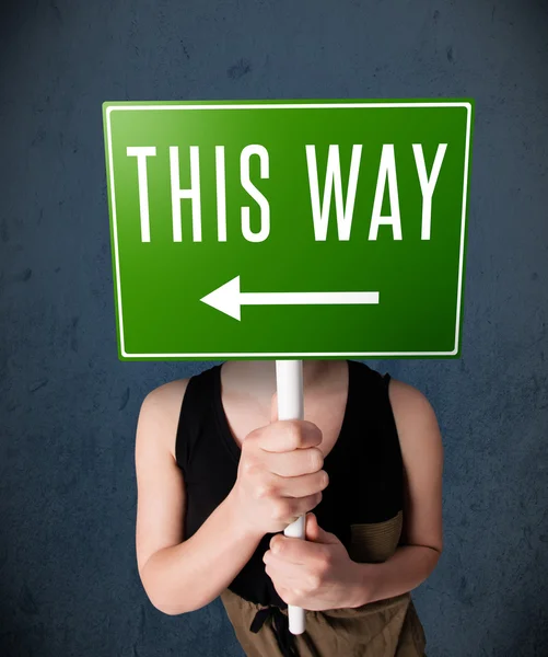 Young woman holding a direction sign — Stock Photo, Image