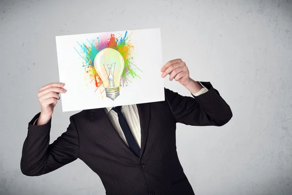 Επιχειρηματίας που κρατά ένα χαρτόνι με πιτσιλιές χρωμάτων και lightbul — Φωτογραφία Αρχείου