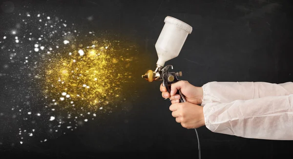 Arbeiter mit Airbrush-Malerei mit glühender goldener Farbe — Stockfoto