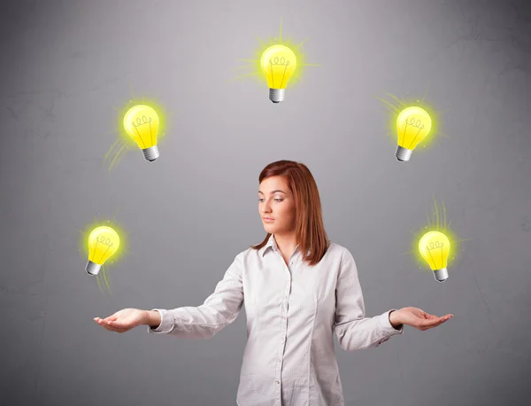 Young lady standing and juggling with light bulbs — Stock Photo, Image