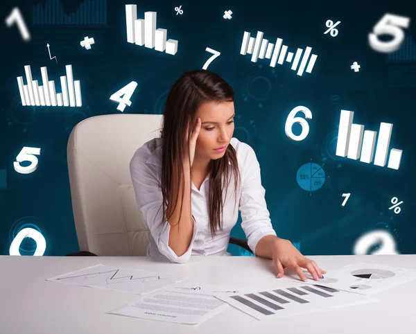 Junge Geschäftsfrau sitzt am Schreibtisch mit Diagrammen und Statistiken — Stockfoto