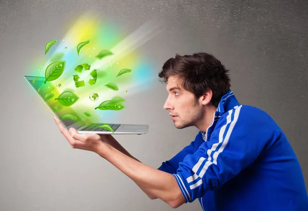 Casual boy holding laptop with recycle and environmental symbols — Stock Photo, Image