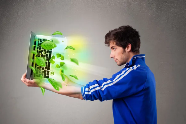 Casual boy holding laptop with recycle and environmental symbols — Stock Photo, Image