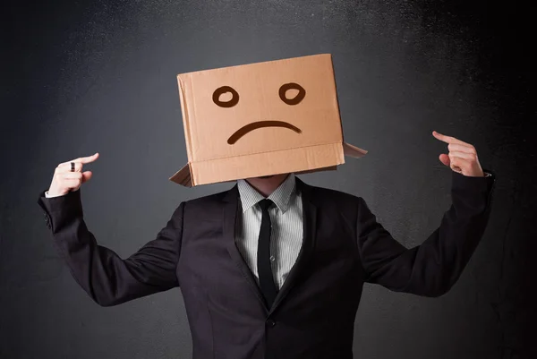 Businessman gesturing with cardboard box on his head with sad fa — Stock Photo, Image