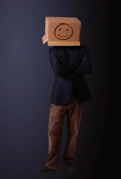 Young man gesturing with a cardboard box on his head with smiley — Stock Photo, Image