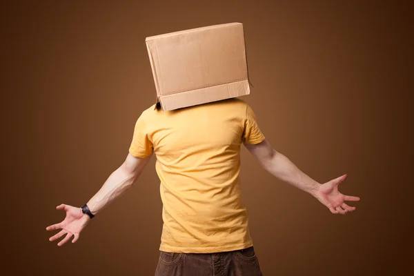 Young man gesturing with a cardboard box on his head — Stock Photo, Image