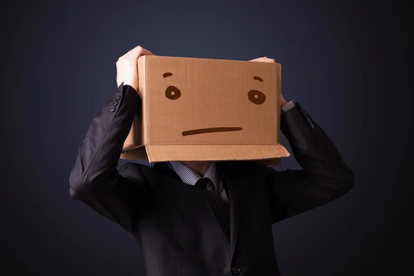 Uomo d'affari gesticolando con una scatola di cartone in testa con stra — Foto Stock