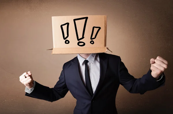 Businessman gesturing with a cardboard box on his head with excl — Stock Photo, Image