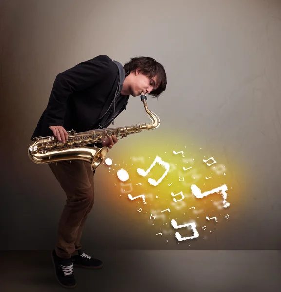 Bonito músico tocando no saxofone com notas musicais — Fotografia de Stock