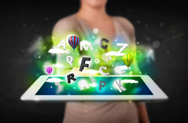 Young person showing tablet with abstract letters and sky — Stock Photo, Image