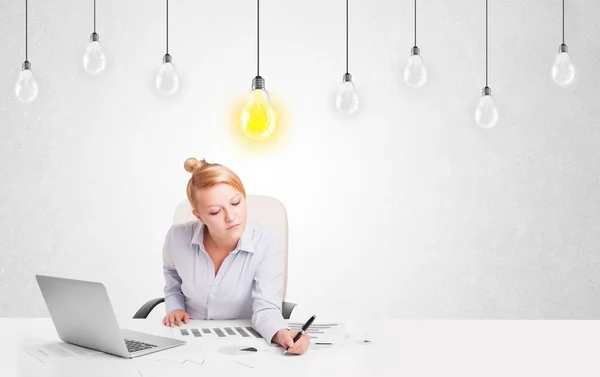 Business woman sitting at table with idea light bulbs — Stock Photo, Image