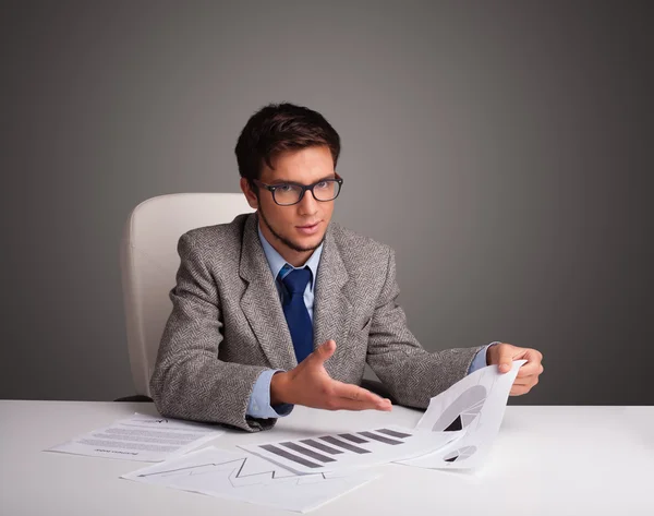 Zakenman zit achter het bureau en doet papierwerk Rechtenvrije Stockafbeeldingen