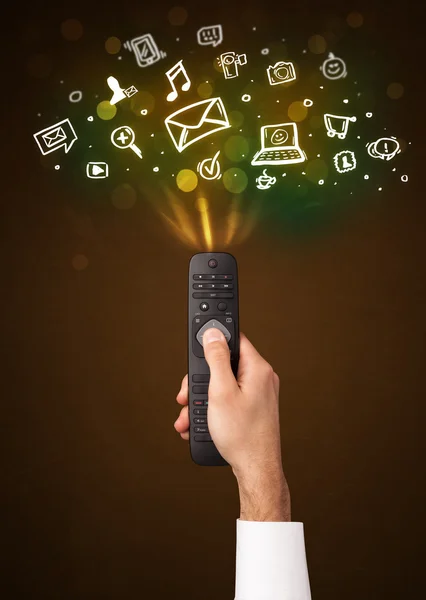 Hand with remote control and social media icons — Stock Photo, Image