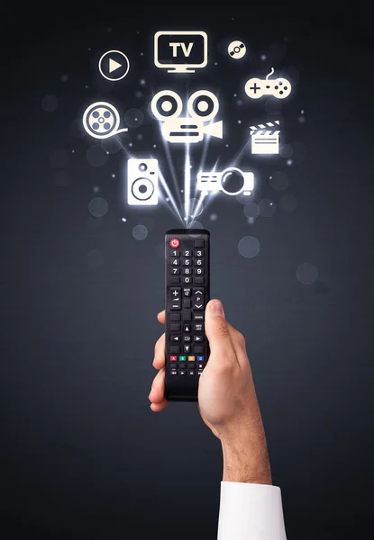 Hand with remote control and media icons — Stock Photo, Image