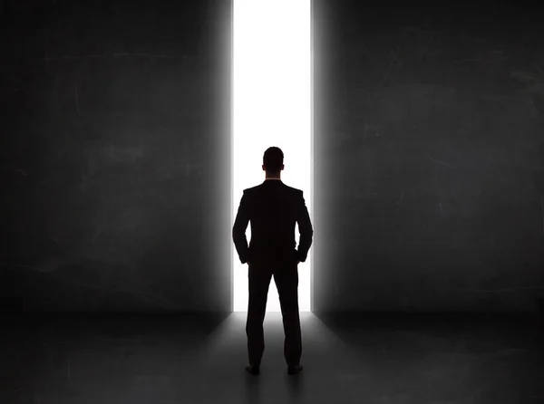 Pessoa de negócios olhando para a parede com abertura do túnel de luz — Fotografia de Stock