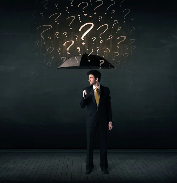 Businessman with umbrella and a lot of drawn question marks — Stock Photo, Image