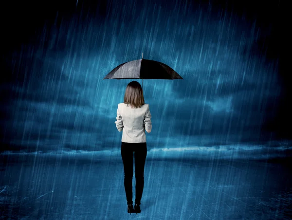 Affärskvinna stående i regnet med ett paraply — Stockfoto