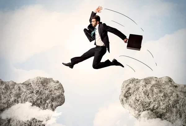 Happy business man jumping over a cliff — Stock Photo, Image