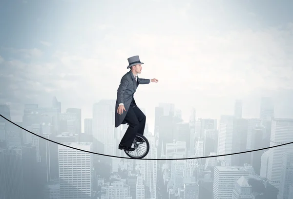 Een dappere man op een monocycle op een touw boven het stadsgezicht. — Stockfoto