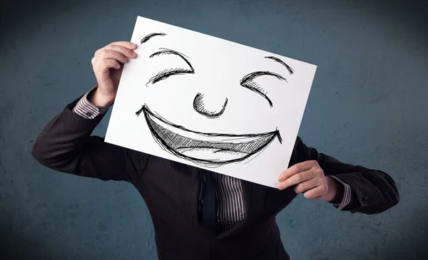 Empresário segurando um papel com rosto sorridente na frente de sua hea — Fotografia de Stock