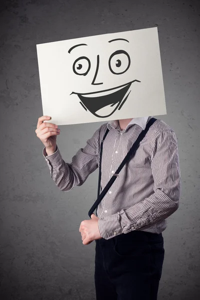 Empresário segurando um papelão com rosto sorridente na frente — Fotografia de Stock