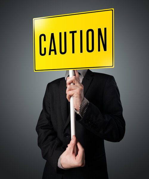 Businessman holding a caution sign