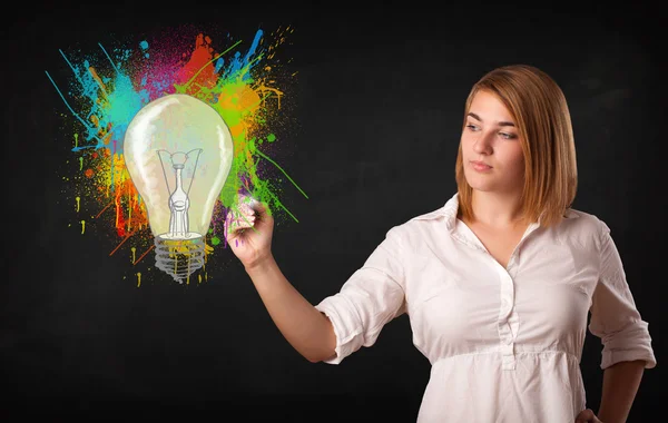 Junge Frau zeichnet eine bunte Glühbirne mit bunten Spritzern — Stockfoto