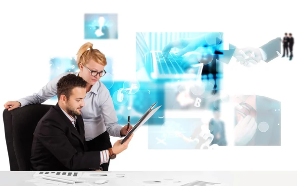 Bedrijfspersonen aan bureau met moderne tech afbeeldingen op de achtergrond — Stockfoto