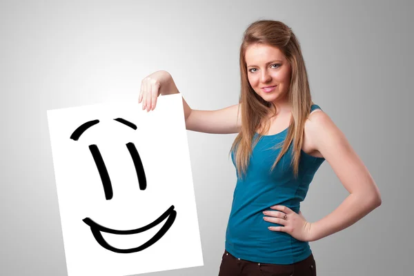 Joven mujer sosteniendo sonriente cara dibujo — Foto de Stock