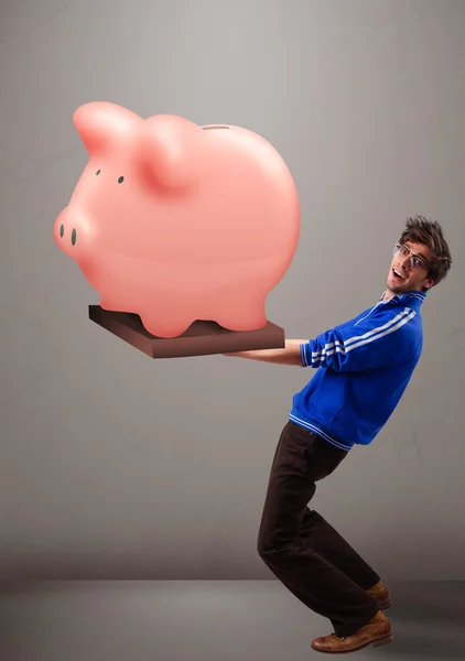 Bonito homem segurando um enorme banco de poupança porquinho — Fotografia de Stock