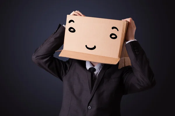 Empresário gesticulando com uma caixa de papelão na cabeça com smil — Fotografia de Stock