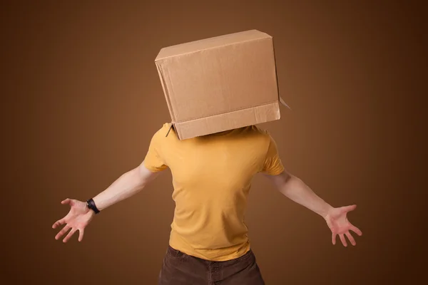 Young man gesturing with a cardboard box on his head — Stock Photo, Image