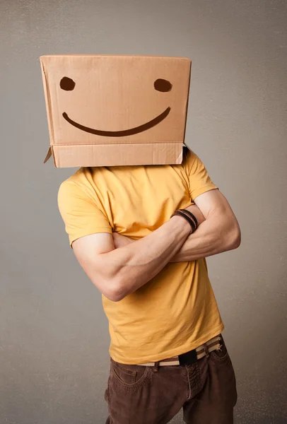 Jeune homme gesticulant avec une boîte en carton sur la tête avec un sourire — Photo