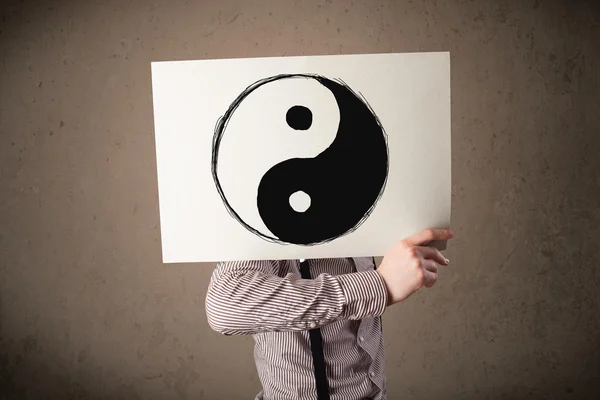 Businessman holding a paper with a yin-yang on it in front of hi — Stock Photo, Image