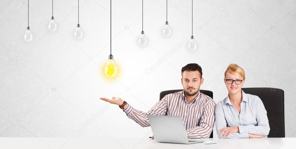 Business man and woman sitting at table with idea light bulbs