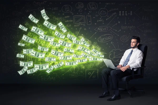 Businessman sitting in chair holding laptop with dollar bills co — Stock Photo, Image