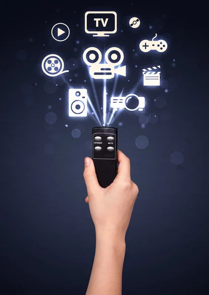 Hand with remote control and media icons — Stock Photo, Image